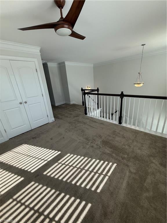 interior space with ceiling fan, ornamental molding, and dark carpet