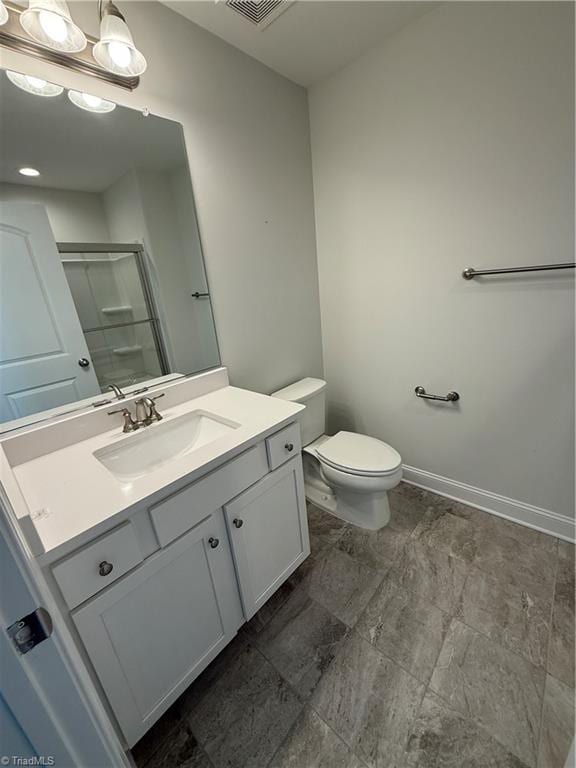 bathroom featuring vanity, toilet, and a shower with shower door