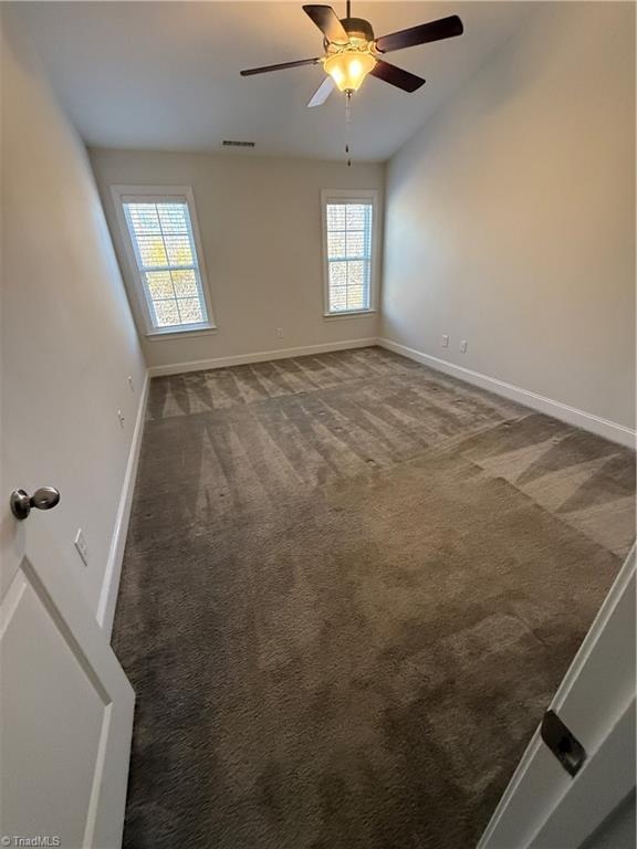 carpeted empty room with a wealth of natural light and ceiling fan