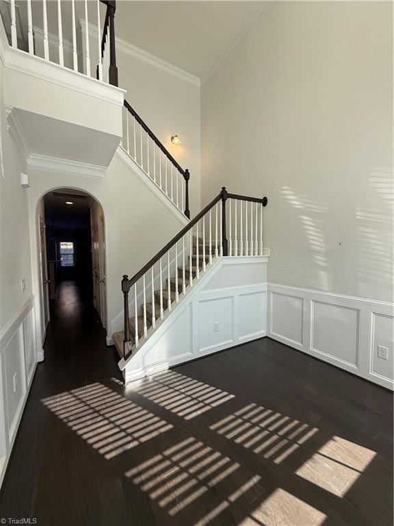 stairs with ornamental molding and hardwood / wood-style floors