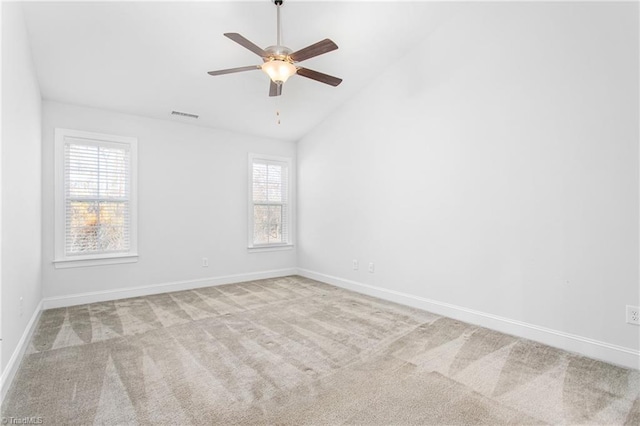 spare room featuring ceiling fan, light colored carpet, vaulted ceiling, and a wealth of natural light