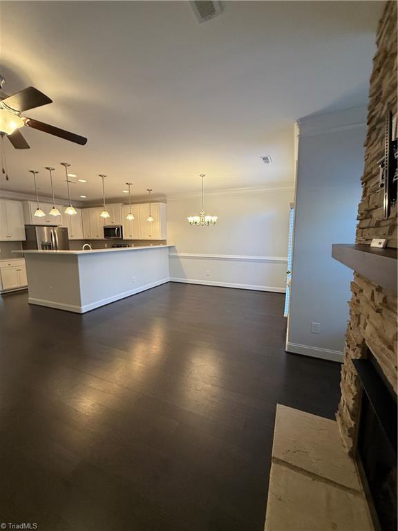 kitchen with ceiling fan with notable chandelier, appliances with stainless steel finishes, white cabinetry, a fireplace, and decorative light fixtures