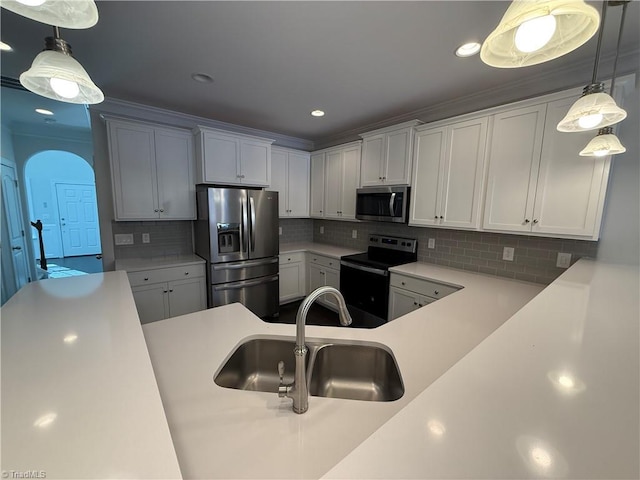 kitchen with pendant lighting, sink, stainless steel appliances, white cabinets, and decorative backsplash