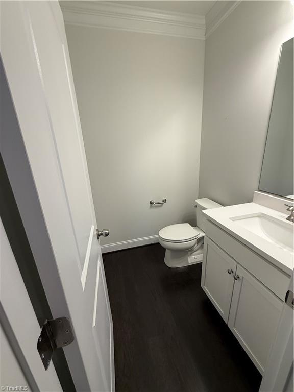 bathroom with vanity, crown molding, wood-type flooring, and toilet