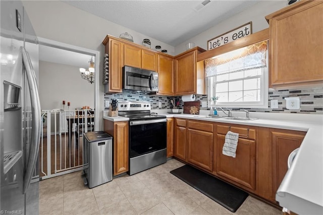 kitchen featuring a sink, visible vents, light countertops, appliances with stainless steel finishes, and brown cabinetry