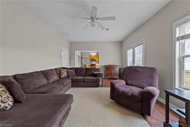 living room featuring ceiling fan with notable chandelier, visible vents, and light wood-style floors