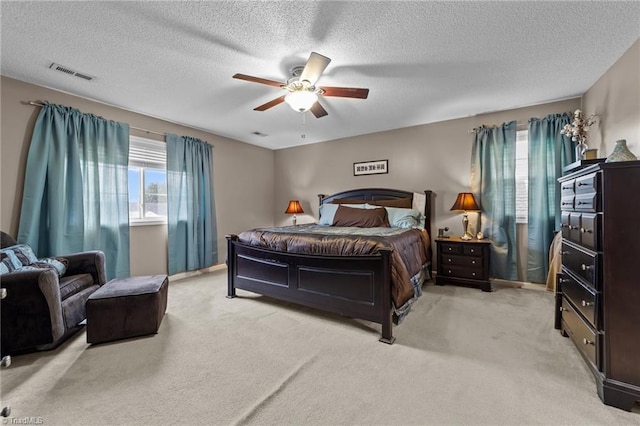 bedroom featuring visible vents, ceiling fan, light carpet, and multiple windows