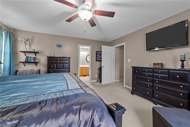 bedroom with a ceiling fan, light carpet, a textured ceiling, ensuite bath, and baseboards