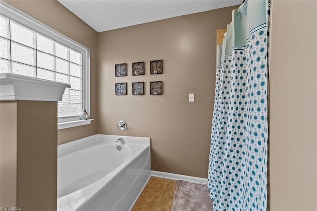 bathroom with a garden tub, tile patterned flooring, and baseboards