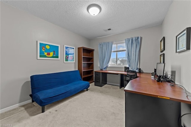 office area with baseboards, visible vents, a textured ceiling, and light colored carpet