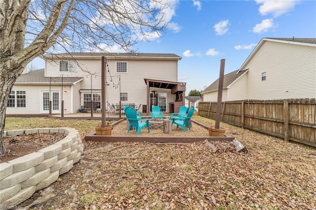 rear view of property with a patio area, a fenced backyard, and a fire pit