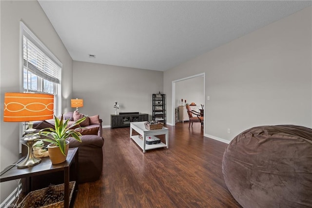 living area with dark wood-style floors, visible vents, and baseboards