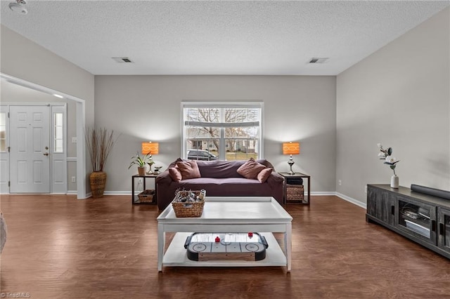 living area with baseboards, visible vents, dark wood finished floors, and a textured ceiling