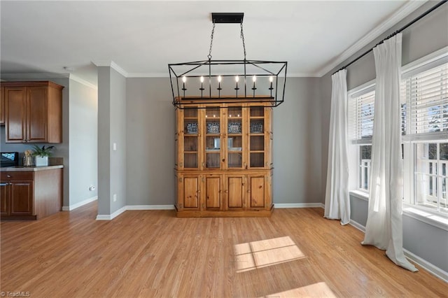 unfurnished dining area with ornamental molding, light wood-style flooring, and baseboards