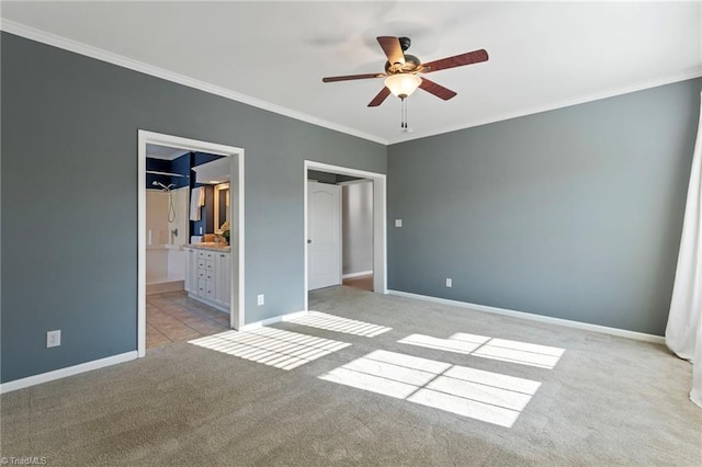 unfurnished bedroom featuring crown molding, light colored carpet, ensuite bathroom, ceiling fan, and baseboards