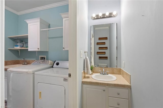 clothes washing area with ornamental molding, washing machine and dryer, cabinet space, and a sink