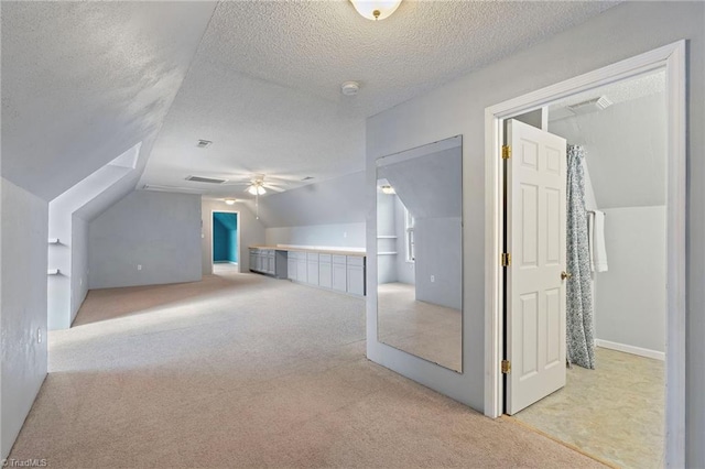 additional living space featuring lofted ceiling, visible vents, a textured ceiling, and light colored carpet