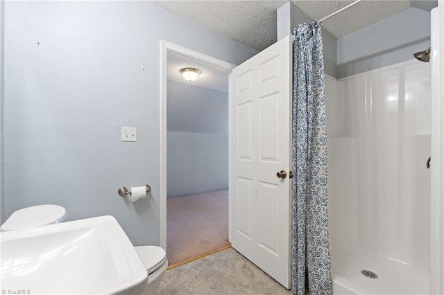 full bathroom featuring a stall shower, a sink, a textured ceiling, and toilet