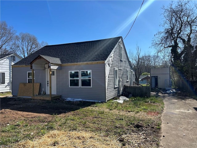 bungalow featuring an outbuilding, fence, and roof with shingles