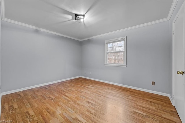 spare room featuring light wood finished floors, baseboards, and crown molding