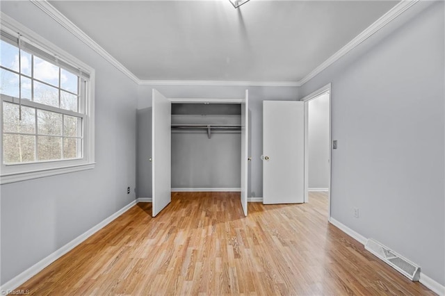 unfurnished bedroom featuring baseboards, visible vents, ornamental molding, wood finished floors, and a closet