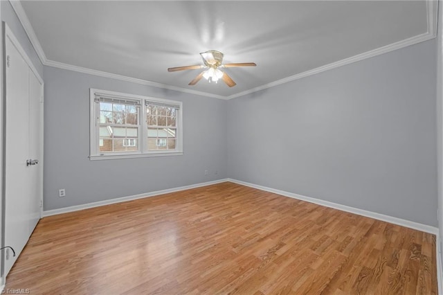 empty room with baseboards, light wood finished floors, a ceiling fan, and crown molding