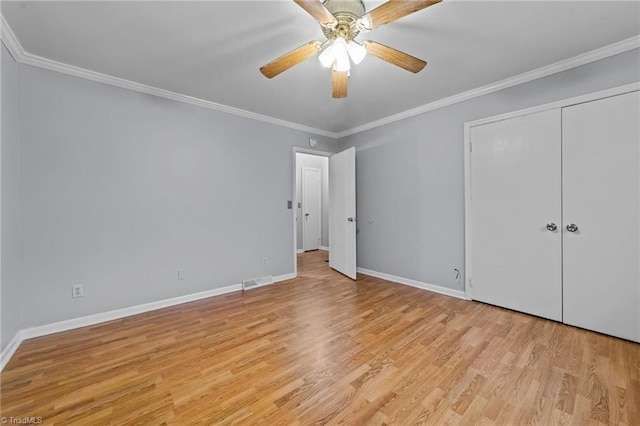 unfurnished bedroom with crown molding, light wood finished floors, a closet, visible vents, and baseboards