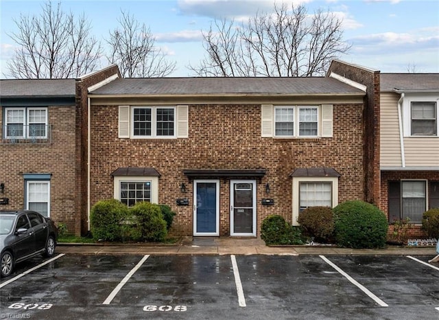 view of property featuring uncovered parking and brick siding