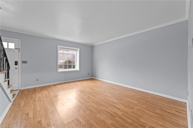 unfurnished room featuring stairs, ornamental molding, light wood-type flooring, and baseboards