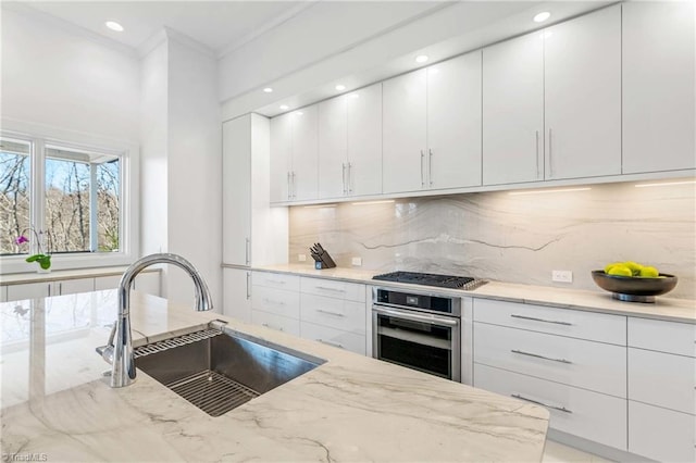 kitchen featuring black gas stovetop, tasteful backsplash, sink, stainless steel oven, and white cabinets