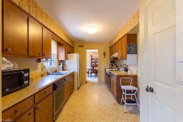 kitchen featuring visible vents, black appliances, under cabinet range hood, a textured ceiling, and light floors