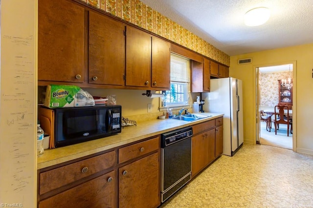 kitchen with visible vents, black appliances, light countertops, a textured ceiling, and a sink