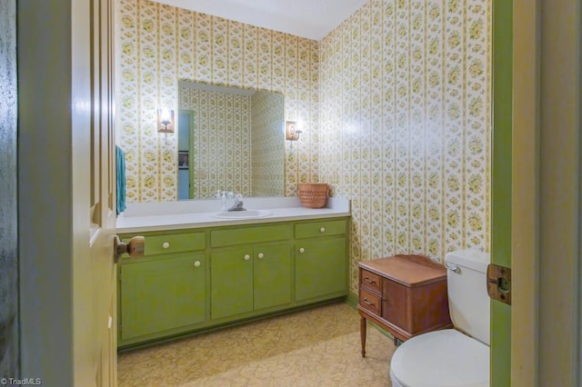 bathroom with wallpapered walls, toilet, and vanity