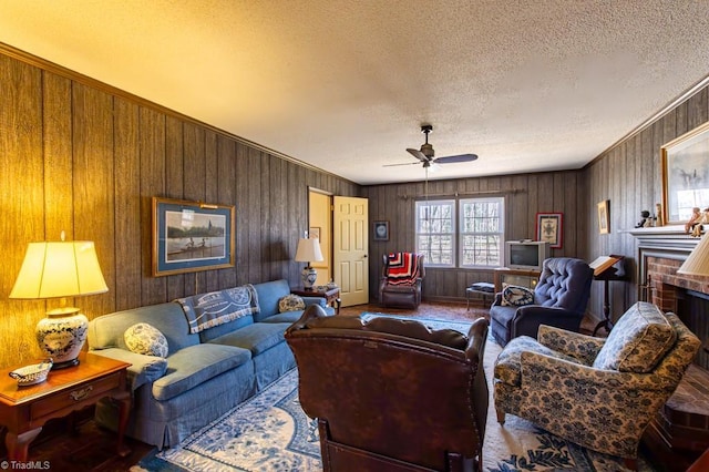 living area with a fireplace, a textured ceiling, and ceiling fan