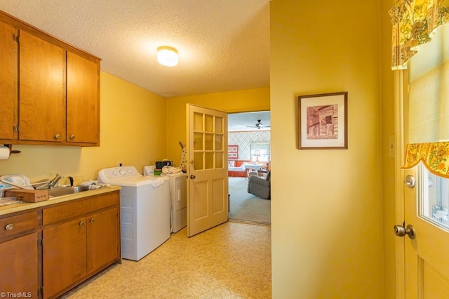 laundry area with light floors, cabinet space, a textured ceiling, independent washer and dryer, and a sink