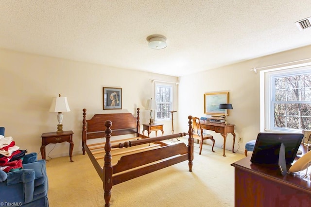 bedroom featuring visible vents, light colored carpet, and a textured ceiling