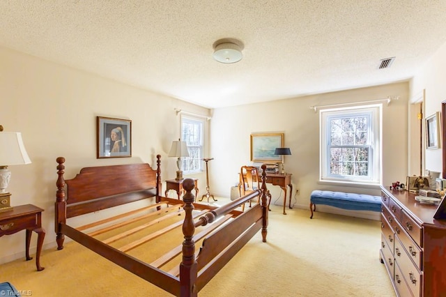 bedroom featuring visible vents, light colored carpet, a textured ceiling, and baseboards