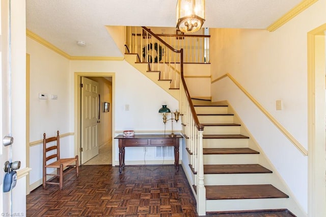 stairs with ornamental molding, baseboards, a chandelier, and a textured ceiling