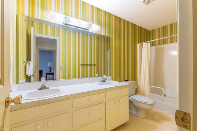 bathroom with toilet, wallpapered walls, and a sink