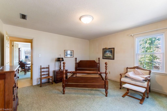 bedroom with a textured ceiling, visible vents, and light carpet