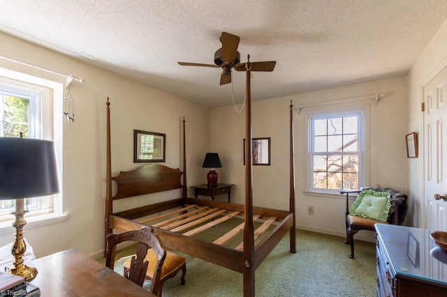 bedroom featuring light colored carpet, a textured ceiling, baseboards, and ceiling fan