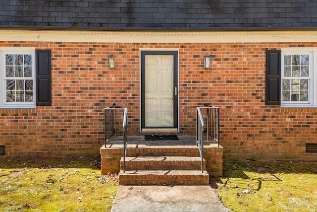 property entrance featuring mansard roof, brick siding, and a shingled roof