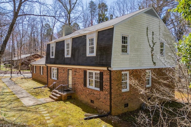 view of home's exterior with crawl space, brick siding, roof with shingles, and a chimney