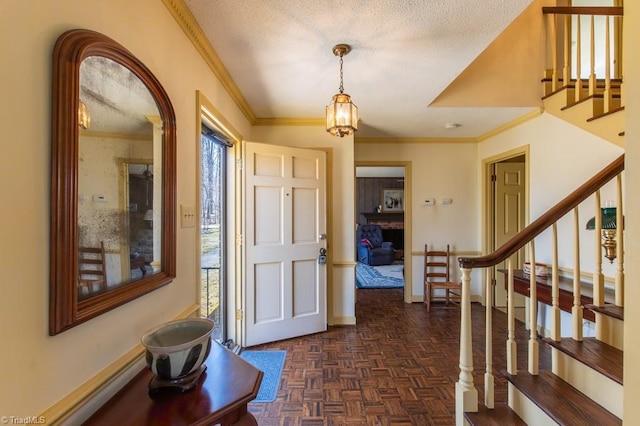 entrance foyer with stairway, baseboards, a textured ceiling, and ornamental molding