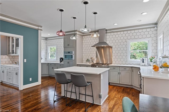 kitchen with oven, backsplash, crown molding, a center island, and wall chimney range hood