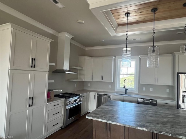 kitchen with pendant lighting, sink, white cabinetry, wall chimney range hood, and stainless steel appliances