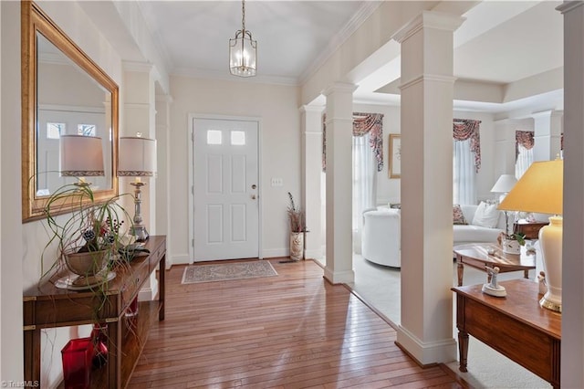 entryway featuring crown molding, light wood-type flooring, and ornate columns