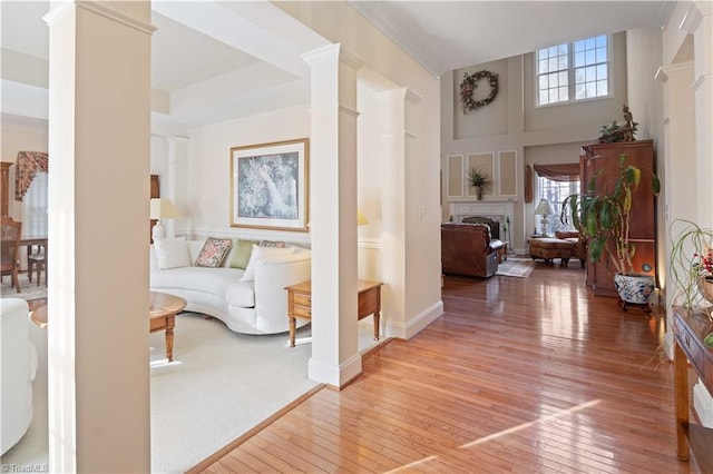 corridor with hardwood / wood-style flooring, decorative columns, and a towering ceiling