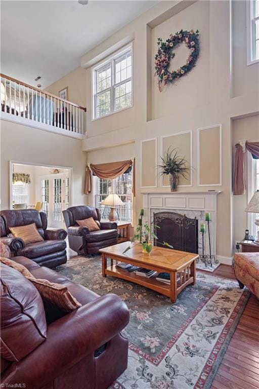 living room featuring a high ceiling, wood-type flooring, and a high end fireplace