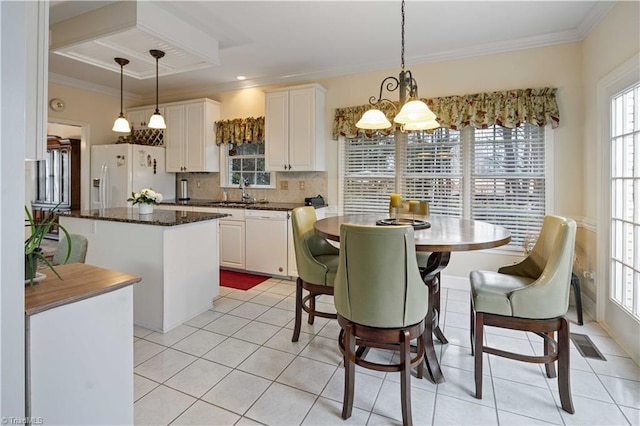 kitchen featuring white cabinetry, a kitchen island, white appliances, and decorative light fixtures